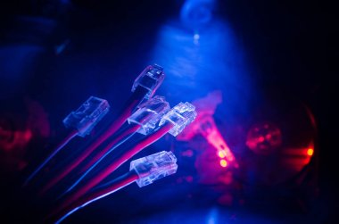 Ağ anahtarı ve ethernet kabloları, global iletişim sembolüdür. Işıklar ve duman ile koyu arka plan üzerinde renkli ağ kabloları. Seçici odak
