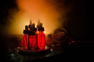 Vape ve Dj Club kavramı. Duman bulutları ve Dj Mikser yakın çekim vape sıvı şişe. Işık efektleri. Arka plan veya vape veya kulüp reklam ya da vape arka plan olarak yararlı.