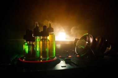 Vape ve Dj Club kavramı. Duman bulutları ve Dj Mikser yakın çekim vape sıvı şişe. Işık efektleri. Arka plan veya vape veya kulüp reklam ya da vape arka plan olarak yararlı.