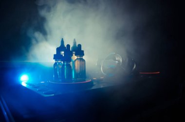 Vape ve Dj Club kavramı. Duman bulutları ve Dj Mikser yakın çekim vape sıvı şişe. Işık efektleri. Arka plan veya vape veya kulüp reklam ya da vape arka plan olarak yararlı.
