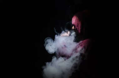 Bir mod tutarak Vaping adam. Buhar bulutu. Siyah arka plan. Vaping çok duman ile elektronik sigara