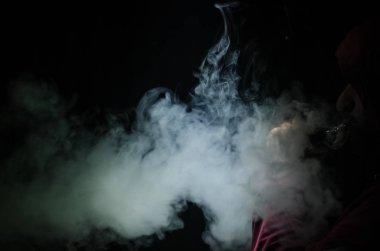 Bir mod tutarak Vaping adam. Buhar bulutu. Siyah arka plan. Vaping çok duman ile elektronik sigara