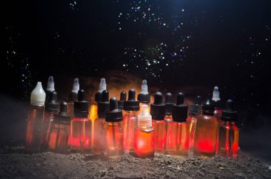 Vape kavramı. Duman bulutları ve vape sıvı şişe koyu arka plan üzerinde. Işık efektleri.