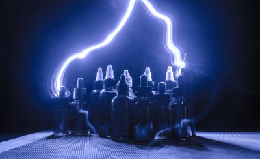 Vape kavramı. Duman bulutları ve vape sıvı şişe koyu arka plan üzerinde. Işık efektleri.