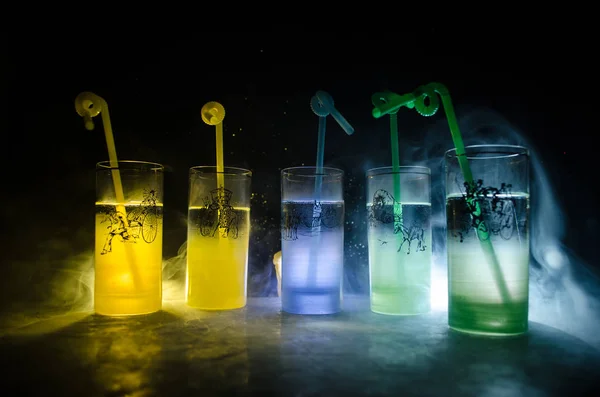 Five cocktails on the bar with smoke on dark background. Yellow, green and blue colored glasses. — Stock Photo, Image