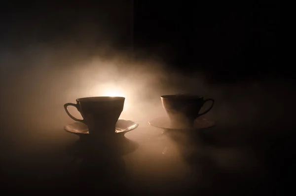 Comida fondo té y café tema. Tetera de cerámica antigua o cafetera con jarra de tazas y taza de azúcar sobre fondo oscuro con luces y humo. Siluetas de tetera y taza de cerámica —  Fotos de Stock