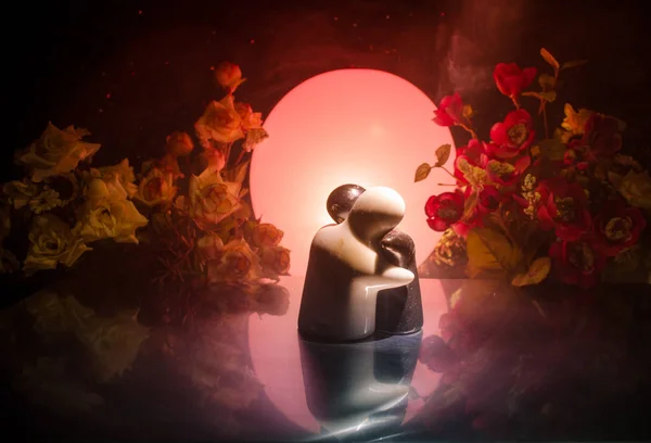 Twee pop knuffelen op tafel met bloemen en maan decoratie oplichtend achtergrond met rook. Begrip van de liefde. Groet of cadeau card design idee. Vintage Toon. Silhouet van het paar knuffelen — Stockfoto