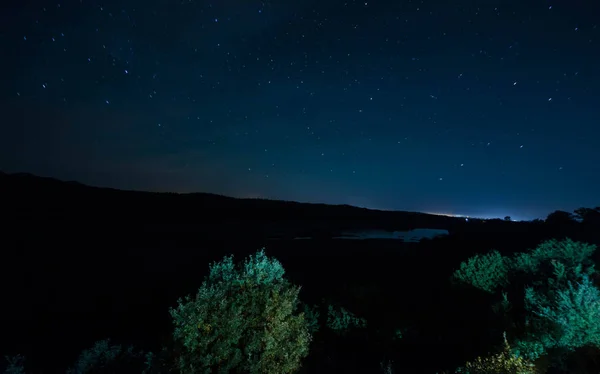 Horská silnice lesem na noc úplňku. Vyhlídkové noční krajina tmavě modré oblohy s měsícem. Ázerbájdžán. Foto dlouho okenice — Stock fotografie