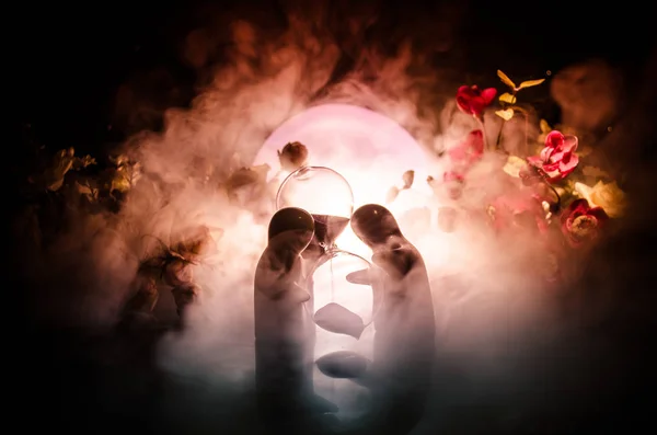 Två docka att kramas på bordet med blommor och måne dekoration upplysta bakgrund med rök. Kärlek-konceptet. Hälsningen eller present kort designidé. Vintage tonen. Silhuetten av Kramande par — Stockfoto
