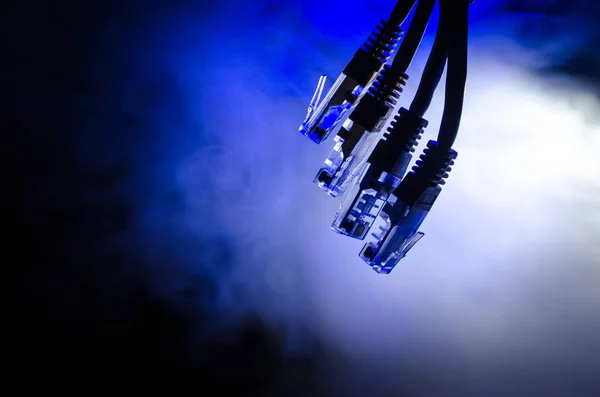Interruttore di rete e cavi ethernet, simbolo delle comunicazioni globali. Cavi di rete colorati su sfondo scuro con luci e fumo. Focus selettivo — Foto Stock