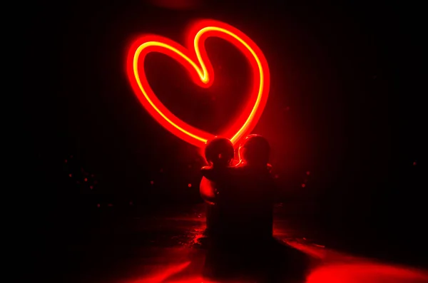 Dos jóvenes amantes pintan un corazón en llamas. Silueta de pareja y palabras de amor sobre un fondo oscuro — Foto de Stock