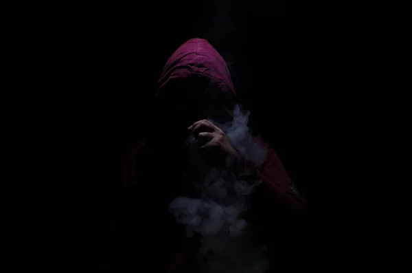 Un voleur tenant un mod. Un nuage de vapeur. Fond noir. Vaping une cigarette électronique avec beaucoup de fumée — Photo