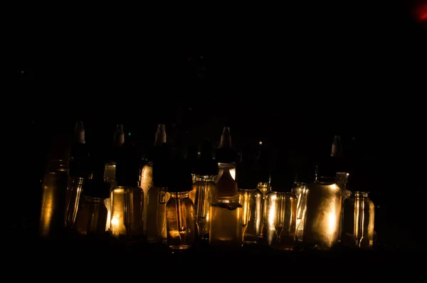 Concepto Vape. Nubes de humo y botellas de vapor líquido sobre fondo oscuro. Efectos luminosos . —  Fotos de Stock