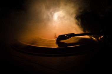 Pikap vinil plak çalar. Retro ses ekipmanları için disk jokey. Dj mix ve müzik çalmak için ses teknolojisi. Yangın arka plan duman ile yanan karşı oynanan vinil kaydı. Vintage