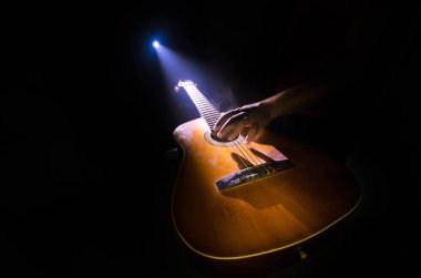 Müzik konsepti. Akustik gitar ile kopya alanı dumanla ışık demeti altında karanlık bir arka plan üzerinde izole. Gitar telleri, yakın çekim. Seçici odak. Yangın etkileri