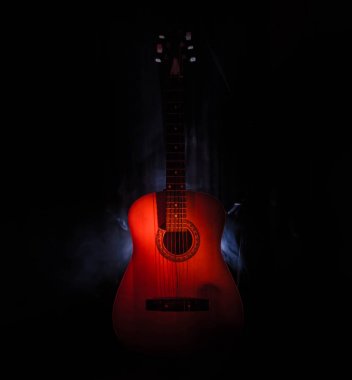 Müzik konsepti. Akustik gitar ile kopya alanı dumanla ışık demeti altında karanlık bir arka plan üzerinde izole. Gitar telleri, yakın çekim. Seçici odak. Yangın etkileri
