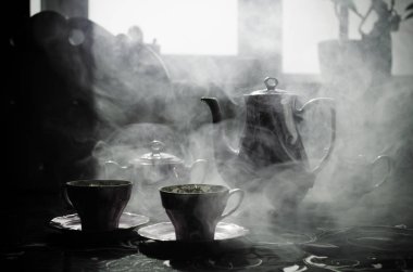 Gıda arka plan Tema çay ve kahve. Eski vintage seramik çay veya kahve ile ışık ve duman koyu arka plan üzerinde bardak sürahi ve şeker Kupası ile. Seramik çaydanlık ve bardak siluetleri