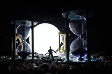 Zaman kavramı. Duman ile hourglasses ve karanlık bir arka plan ışıkları arasında duran bir adam silüeti.