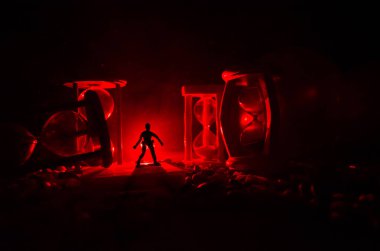 Zaman kavramı. Duman ile hourglasses ve karanlık bir arka plan ışıkları arasında duran bir adam silüeti.