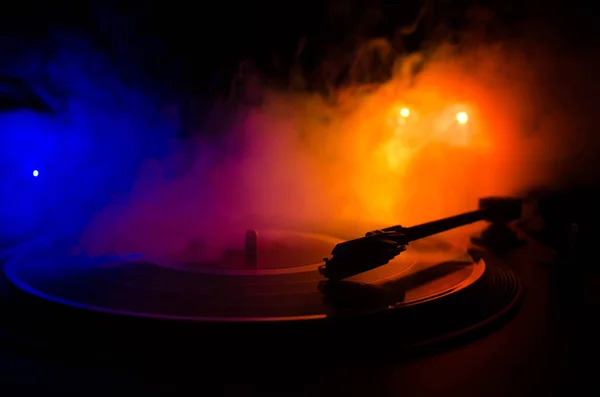 Turntable vinyl record player. Retro audio equipment for disc jockey. Sound technology for DJ to mix & play music. Vinyl record being played against burning fire background with smoke. Vintage — Stock Photo, Image