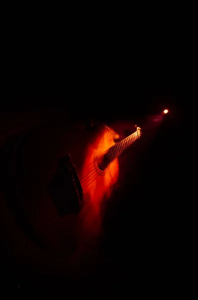 Concepto musical. Guitarra acústica aislada sobre un fondo oscuro bajo haz de luz con humo con espacio de copia. Cuerdas de Guitarra, de cerca. Enfoque selectivo. Efectos de fuego —  Fotos de Stock