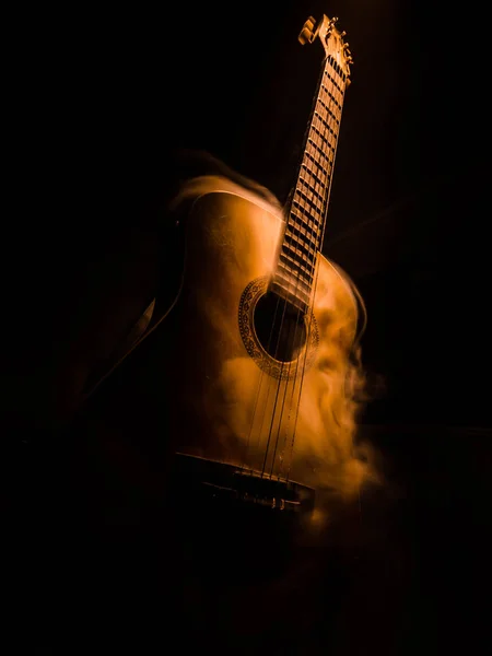 Conceito musical. Guitarra acústica isolada em fundo escuro sob feixe de luz com fumaça com espaço de cópia. Cordas de guitarra, de perto. Foco seletivo. Efeitos de fogo — Fotografia de Stock