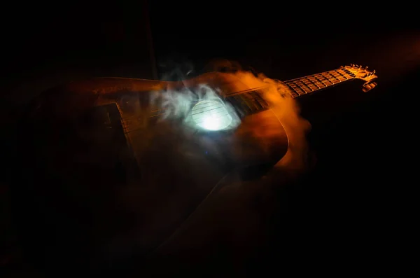 Musikkonzept. Akustikgitarre isoliert auf dunklem Hintergrund unter Lichtkegel mit Rauch und Kopierraum. Gitarrensaiten, hautnah. Selektiver Fokus. Feuereffekte — Stockfoto