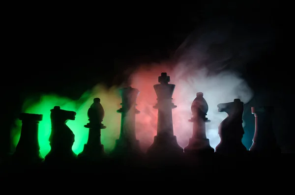 Chess board game concept of business ideas and competition and strategy ideas concep. Chess figures on a dark background with smoke and fog — Stock Photo, Image