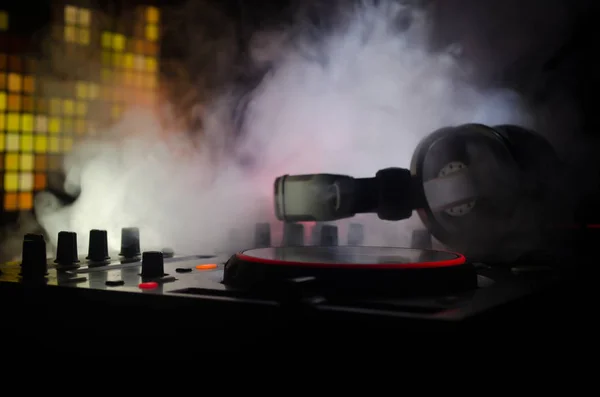 DJ Spinning, Mixing, and Scratching in a Night Club, Manos de dj ajustar varios controles de pista en la cubierta de dj, luces estroboscópicas y niebla, enfoque selectivo —  Fotos de Stock