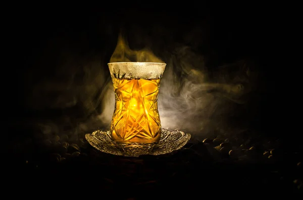 Turkish Azerbaijan tea in traditional glasse and pot on black background with lights and smoke. Armudu traditional cup