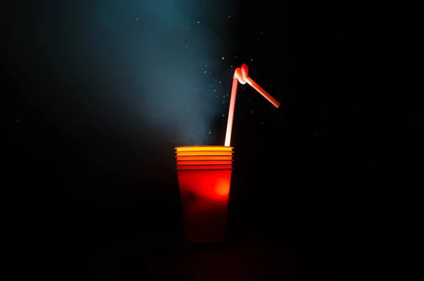 Montón de tazas de plástico naranja con paja sobre fondo oscuro — Foto de Stock
