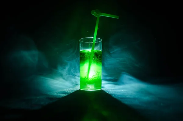 Glas groen cocktail met stro op donkere achtergrond met rook en achtergrondverlichting. — Stockfoto