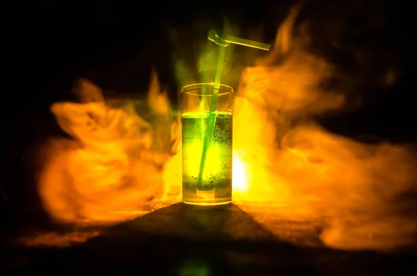 Copo de coquetel verde com palha no fundo escuro com fumaça e backlights . — Fotografia de Stock