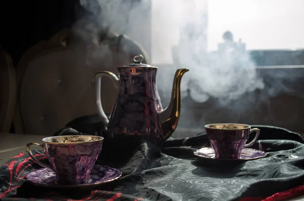 Essen Hintergrund Tee und Kaffee Thema. alte Vintage-Keramik-Tee- oder Kaffeekanne mit Tassen-Kanne und Zuckerbecher auf dunklem Hintergrund mit Licht und Rauch. Silhouetten von Teekanne und Tasse aus Keramik — Stockfoto