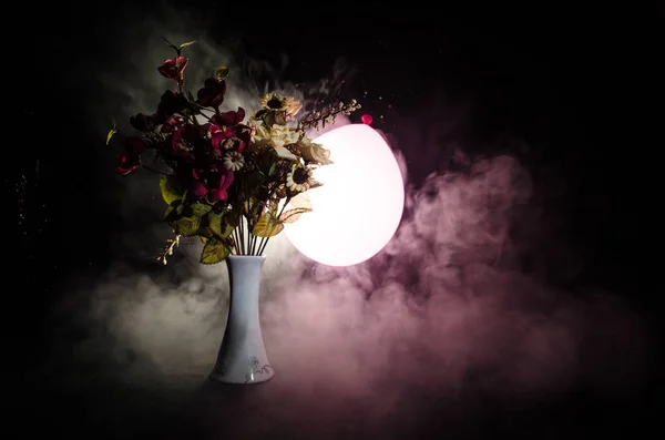 Pintorescas flores de primavera púrpura en jarrón de vidrio de pie en una fila sobre un fondo oscuro con estrellas con luz y niebla. De cerca. — Foto de Stock