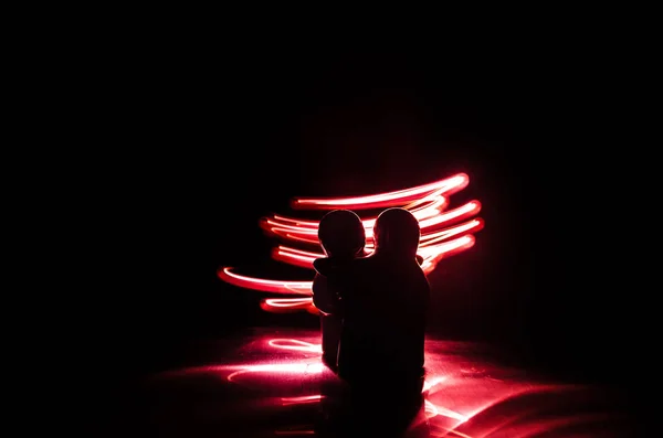 Dva mladí milenci malovat srdce v ohni. Silueta páru a lásku slova na tmavém pozadí — Stock fotografie