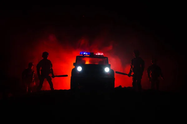 La policía antidisturbios da la señal de estar listo. Concepto de poder gubernamental. Policía en acción. Fuma sobre un fondo oscuro con luces. Sirenas azules rojas intermitentes. Poder de la dictadura. Enfoque selectivo — Foto de Stock