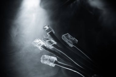 Ağ anahtarı ve ethernet kabloları, global iletişim sembolüdür. Işıklar ve duman ile koyu arka plan üzerinde renkli ağ kabloları. Seçici odak