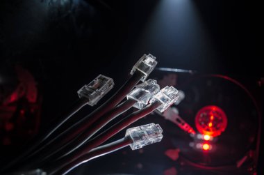 Ağ anahtarı ve ethernet kabloları, global iletişim sembolüdür. Işıklar ve duman ile koyu arka plan üzerinde renkli ağ kabloları. Seçici odak