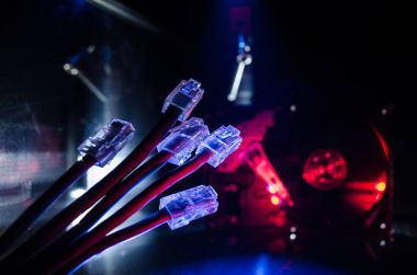 Ağ anahtarı ve ethernet kabloları, global iletişim sembolüdür. Işıklar ve duman ile koyu arka plan üzerinde renkli ağ kabloları. Seçici odak