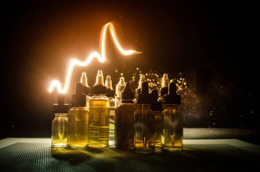 Vape kavramı. Duman bulutları ve vape sıvı şişe koyu arka plan üzerinde. Işık efektleri.