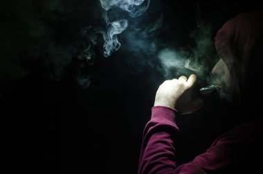Bir mod tutarak Vaping adam. Buhar bulutu. Siyah arka plan. Vaping çok duman ile elektronik sigara
