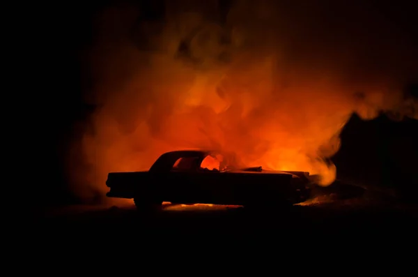 Brinnande bil på en mörk bakgrund. Bilen fattar eld, efter lagen av vandalism eller road indicent — Stockfoto