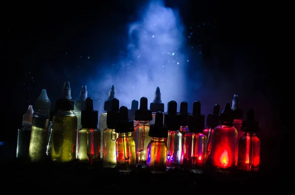 Koncepcja Vape. Pali, chmury i vape płyn butelki na ciemnym tle. Efekty świetlne. — Zdjęcie stockowe
