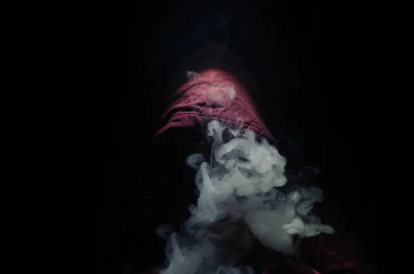 Hombre aspirante sosteniendo un mod. Una nube de vapor. Fondo negro. Vapeando un cigarrillo electrónico con mucho humo — Foto de Stock