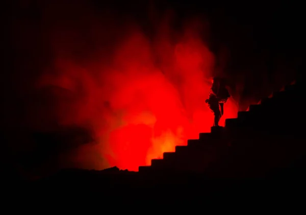 Uma silhueta de um homem agarrado à mulher. Conceito de salvamento de salvamento. Fuja do fogo ou do perigo. Ampulheta, Fogo — Fotografia de Stock