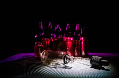 Vape kavramı. Duman bulutları ve vape sıvı şişe koyu arka plan üzerinde. Işık efektleri.