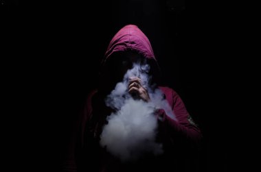 Bir mod tutarak Vaping adam. Buhar bulutu. Siyah arka plan. Vaping çok duman ile elektronik sigara