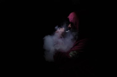 Bir mod tutarak Vaping adam. Buhar bulutu. Siyah arka plan. Vaping çok duman ile elektronik sigara