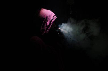 Bir mod tutarak Vaping adam. Buhar bulutu. Siyah arka plan. Vaping çok duman ile elektronik sigara